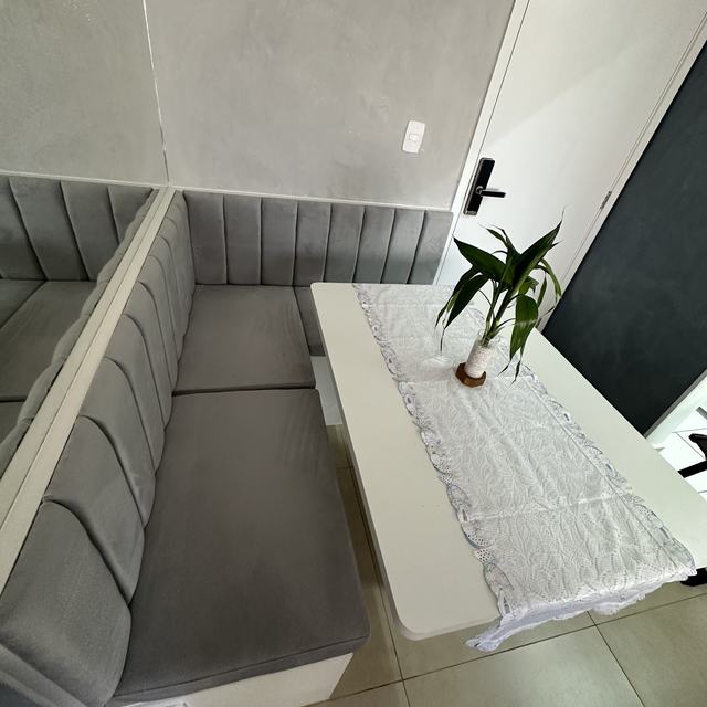 Banco de canto cinza com encosto em gomos junto à mesa da cozinha