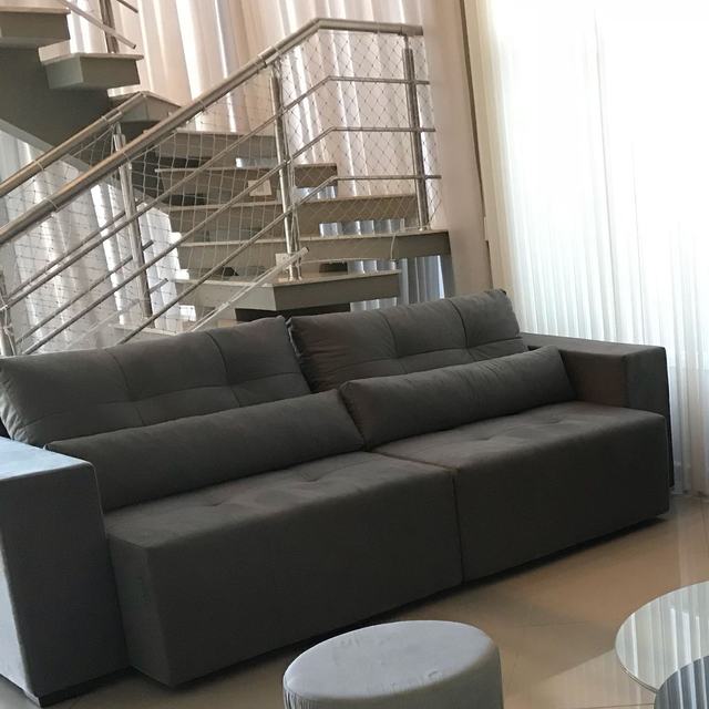 Sofá retrátil cinza na sala, ao lado da escada